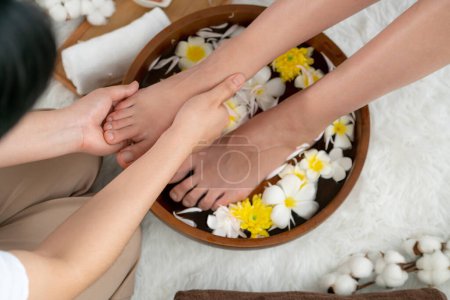 Téléchargez les photos : Femme se livre à un massage des pieds heureux au salon de spa de luxe tandis que masseur donner thérapie de réflexologie dans une douce ambiance de lumière du jour station ou spa des pieds de l'hôtel. Tranquillité - en image libre de droit