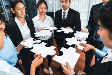 Photo for Multiethnic business people holding jigsaw pieces and merge them together as effective solution solving teamwork, shared vision and common goal combining diverse talent. Meticulous - Royalty Free Image