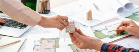 Photo for Professional engineer and architect collaborate on eco house project at meeting table with green design blueprint and architectural equipment at modern office. Focus on hand. Close up. Delineation. - Royalty Free Image