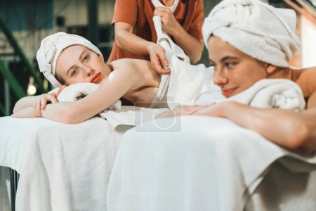 Photo for A portrait of a couple of a beautiful young caucasian woman with white towel rest on comfortable spa bed with relaxation while having body massage with professional masseur at spa salon.Tranquility. - Royalty Free Image
