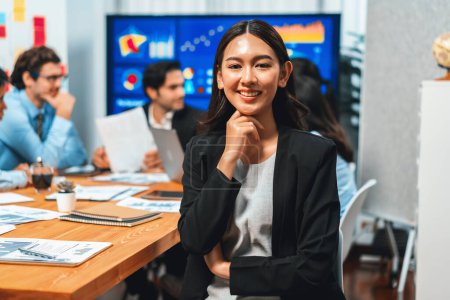 Téléchargez les photos : Portrait d'une jeune femme d'affaires asiatique heureuse ou analyste regardant la caméra avec son collègue analyser l'analyse des données dans une réunion dynamique de planification des investissements en stratégie d'entreprise. Habillement - en image libre de droit