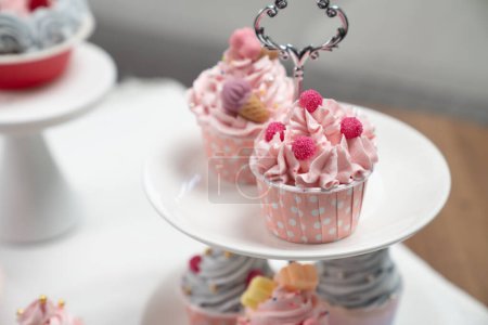 Téléchargez les photos : Pièce de présentation de cupcake sur gâteau blanc debout avec pot à thé mis en concept de couleurs pastel cuisine spéciale. Contenu créatif des médias sociaux avec plat préféré de boulangerie de bonbons. Tastemaker. - en image libre de droit