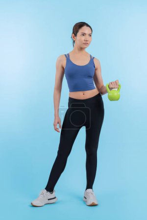 Photo for Vigorous energetic woman doing kettlebell weight lifting exercise on isolated background. Young athletic asian woman strength and endurance training session as body workout routine. - Royalty Free Image