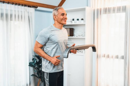Photo for Active senior man running on tread running machine at home together as fitness healthy lifestyle and body care after retirement for pensioner. Clout - Royalty Free Image