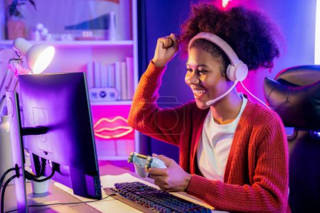 Photo for African American girl streamer playing online fighting with Esport skilled team wearing headphones in neon color lighting room. Talking other players planing strategies to win competitors. Tastemaker. - Royalty Free Image
