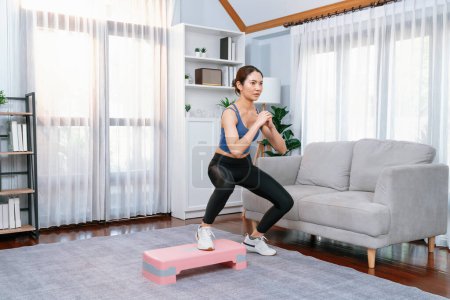 Photo for Vigorous energetic woman doing exercise at home, cardio aerobic step workout. Young athletic asian woman dexterity and endurance training session as home workout routine concept. - Royalty Free Image