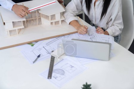 Photo for Professional engineer measures house model while skilled designer writes down in blueprint. Work together, collaboration, cooperate. Creative design and team working concept. Top view. Immaculate. - Royalty Free Image