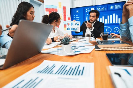 Photo for Diverse group of business analyst team analyzing financial data report. Finance data analysis chart and graph dashboard show on TV screen in meeting room for strategic marketing planning. Habiliment - Royalty Free Image