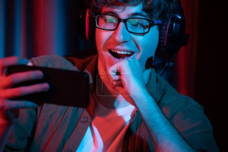 Photo for Young gaming streamer team getting winner players with Esport online on smartphone fighting wearing headphones at neon light room. Practising strategy plan to win competitors for next level. Gusher. - Royalty Free Image