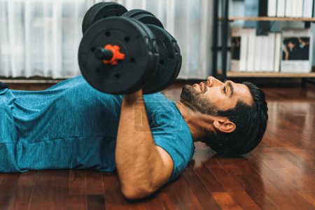 Photo for Athletic body and active sporty man lifting dumbbell weight for effective targeting muscle gain at gaiety home as concept of healthy fit body home workout lifestyle. - Royalty Free Image