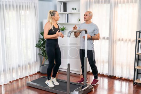 Photo for Active senior couple running on tread running machine at home together in full body shot as fitness healthy lifestyle and body care after retirement for pensioner. Clout - Royalty Free Image