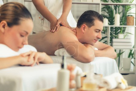 Téléchargez les photos : Couple caucasien client appréciant relaxant massage spa anti-stress et dorloter avec beauté loisirs de la peau dans la lumière du jour salon de spa ambiant à la station de luxe ou hôtel. Tranquillité - en image libre de droit