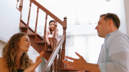Téléchargez les photos : Une jeune fille stressée et malheureuse regarde son parent se disputer depuis l'escalier. La violence domestique à la maison et l'enfance traumatisante se transforment en dépression et en anxiété. Concept familial malsain. Synchronos - en image libre de droit