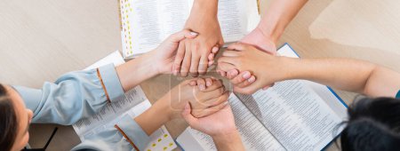 Photo for Cropped image of diversity people hand praying together at wooden church on bible book while hold hand together with believe. Concept of faith, god blessing concept. Top view. Burgeoning. - Royalty Free Image