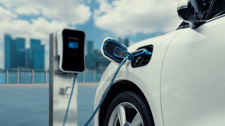Photo for Electric car plugged in with charging station to recharge battery with electricity by EV charger cable with city background. Future innovative ev car and energy sustainability. Peruse - Royalty Free Image