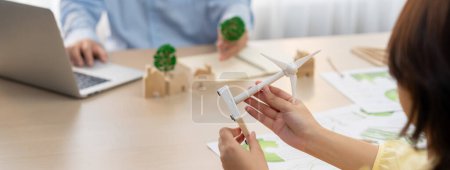 Photo for Businesswoman interested in investing in renewable energy at meeting table with environmental document scatter around. Business team discussion about green business project. Closeup. Delineation. - Royalty Free Image
