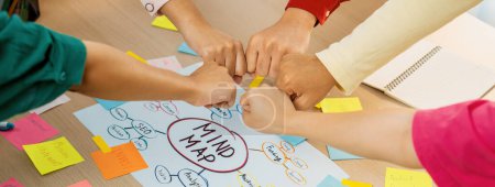 Photo for Young happy creative startup group join circle fist bump hands together surrounded by marketing strategy mind map and colorful sticky notes at meeting room. Unity and teamwork concept. Variegated. - Royalty Free Image