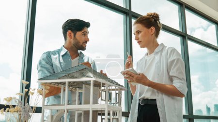 Photo for Skilled architect engineer team discussion about house model construction. Smart interior designer sharing, talking about building design while beautiful coworker taking a note. Design. Tracery - Royalty Free Image