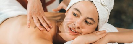 Photo for Beautiful young woman received a back massage on a spa bed from professional masseuse. Attractive female relaxes deeply by skilled hands of the massage therapist. Surrounded with nature. Tranquility. - Royalty Free Image