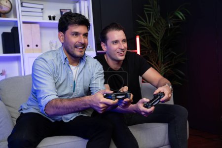 Photo for Winner and loser players of buddy friend gamers playing video game on TV using joysticks in studio room with neon blue light. Comfy living indoor at home place with cheerful fighting winner. Sellable. - Royalty Free Image