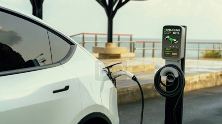 Téléchargez les photos : Batterie de recharge de voiture électrique à la station de recharge extérieure EV pour le voyage sur la route ou en voiture voyageant par le paysage marin, technologie d'énergie alternative et durable pour voiture écologique. Perpétuel - en image libre de droit