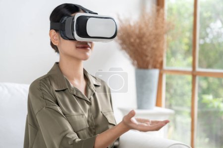 Photo for Young woman using virtual reality VR goggle at home for uttermost online shopping experience. The virtual reality VR innovation optimized for digital entertainment lifestyle. - Royalty Free Image