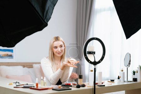 Photo for Young woman making beauty and cosmetic tutorial video content for social media. Beauty blogger smiles to camera while showing how to apply beauty skincare to audience or followers. Blithe - Royalty Free Image