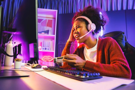 Photo for African American girl streamer disappointed playing online fighting with Esport skilled team wearing headphones in neon room. Talking other players planing strategies to win competitors. Tastemaker. - Royalty Free Image
