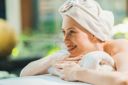 Photo for Closeup of beautiful women in white towel relaxes on spa bed surrounded by peaceful and calm nature. Young gorgeous female wearing white towel during waiting for body massage. Side view. Tranquility - Royalty Free Image