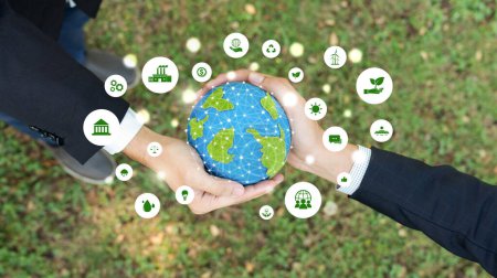 Téléchargez les photos : Deux hommes d'affaires tenant la planète Terre ensemble symbolisent l'engagement du partenariat ESG en faveur de la protection de l'environnement en utilisant les énergies renouvelables pour réduire le carbone sur une Terre plus verte. - en image libre de droit