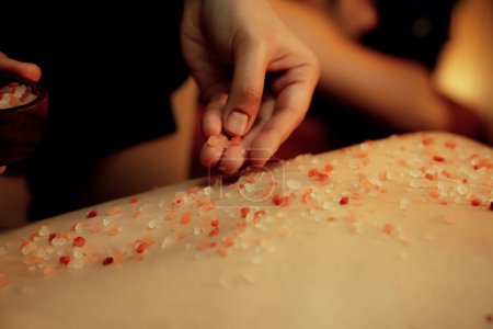 Photo for Closeup woman customer having exfoliation treatment in luxury spa salon with warmth candle light ambient. Salt scrub beauty treatment in Health spa body scrub. Quiescent - Royalty Free Image