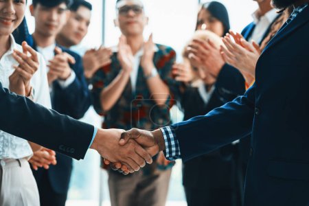 Photo for Cropped image of businessmen shaking hand and making a contract in the sign of agreement, cooperation rounded with smiling employees clapping hands and applause behind. Front view. Intellectual. - Royalty Free Image