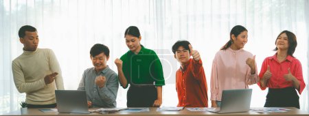 Photo for Happy young creative business team celebrate their success together at meeting table with business document and laptop placed on the table. Creative and success start up concept. Variegated. - Royalty Free Image
