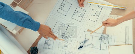Photo for Blueprint architectural document scatter around on meeting table while professional architect engineer hand pointing at blueprint. Creative design teamwork discussion concept. Top view. Burgeoning. - Royalty Free Image