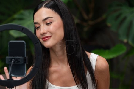 Photo for Young woman making natural beauty and cosmetic tutorial on green plant garden video content for social media. Beauty celebrity blogger showing how to beauty care to audience or followers. Blithe - Royalty Free Image