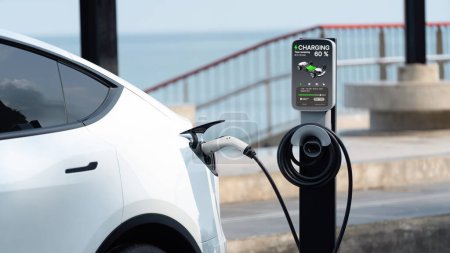 Photo for Electric car recharging battery at outdoor EV charging station for road trip or car traveling by the seascape, alternative and sustainable energy technology for eco-friendly car. Perpetual - Royalty Free Image