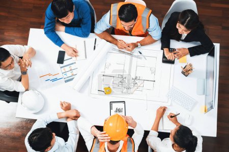 Photo for Top view banner of diverse group of civil engineer and client working together on architectural project, reviewing construction plan and building blueprint at meeting table. Prudent - Royalty Free Image