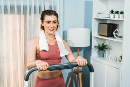 Photo for Athletic and sporty woman running on treadmill running machine during home body workout exercise session for fit physique and healthy sport lifestyle at home. Gaiety home exercise workout training. - Royalty Free Image