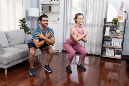 Photo for Athletic and sporty couple doing squat together during home body workout exercise session for fit physique and healthy sport lifestyle at home. Gaiety home exercise workout training concept. - Royalty Free Image