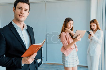 Photo for Happy young handsome businessman reading book and working in office with colleagues and friend at workplace. Corporate business people group. uds - Royalty Free Image