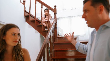 Téléchargez les photos : Une jeune fille stressée et malheureuse regarde son parent se disputer depuis l'escalier. La violence domestique à la maison et l'enfance traumatisante se transforment en dépression et en anxiété. Concept familial malsain. Synchronos - en image libre de droit
