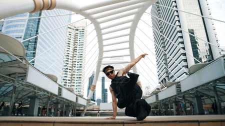 Téléchargez les photos : Jeune hipster asiatique montrent pas à pas au centre-ville entourent par les gens. Élégant danseur de rue mode effectuer B-boy ou freestyle danse avec un angle bas. Sport de plein air 2024. Pause dansante. Brillamment. - en image libre de droit