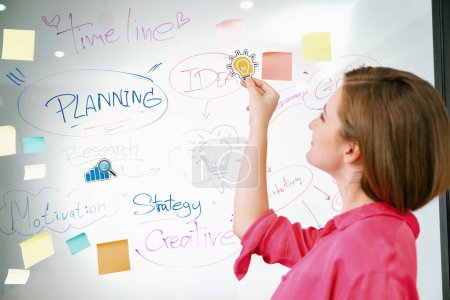 Photo for Young beautiful businesswoman putting sticker on glass board while finding a solution to solve financial problems by using mind map and colorful sticky note. Creative business concept. Immaculate. - Royalty Free Image