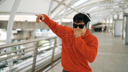 Photo for Professional hipster move hands to music listening from headphone while beat box to hip hop song. Break dancer wearing headphone and stylish cloth. Modern lifestyle. Outdoor sport 2024 Sprightly. - Royalty Free Image