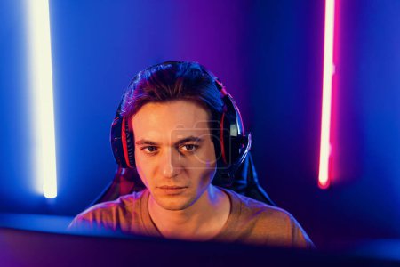 Photo for Host channel of gaming smart streamer playing online game to be winner, wearing headphone with viewers live steaming on media social online for selected team competition at neon light room. Pecuniary. - Royalty Free Image