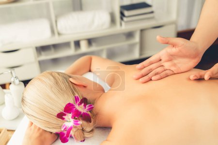 Photo for Closeup woman customer enjoying relaxing anti-stress spa massage and pampering with beauty skin recreation leisure in day light ambient salon spa at luxury resort or hotel. Quiescent - Royalty Free Image