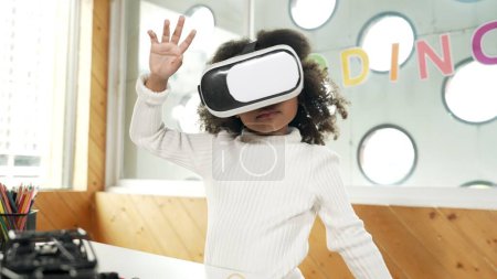 Photo for Creative girl wearing VR headset to learning in metaverse. Funny kid enjoy to wearing AI headset and enter to virtual world program in STEM technology class. Innovation. Future lifestyle. Erudition. - Royalty Free Image
