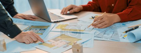 Photo for A portrait of skillful architect discussing with his coworker about house construction design during using laptop. Professional engineers choose house plan carefully. Closeup. Delineation. - Royalty Free Image