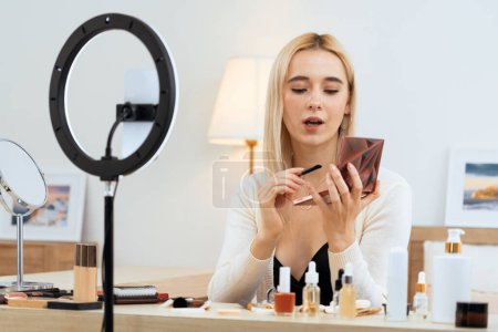 Photo for Young woman making beauty and cosmetic tutorial video content for social media. Beauty blogger smiles to camera while showing how to beauty care to audience or followers. Blithe - Royalty Free Image