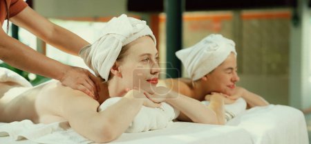 Téléchargez les photos : Couple de belle jeune femme allongée sur un lit de spa blanc pendant le massage du dos. Belle femme caucasienne ayant massage du dos à la salle de spa traditionnelle. Concept relaxant et sain Tranquillité. - en image libre de droit